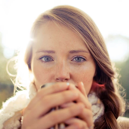 Portrait einer jungen Frau, die eine Teetasse in beiden Händen holt